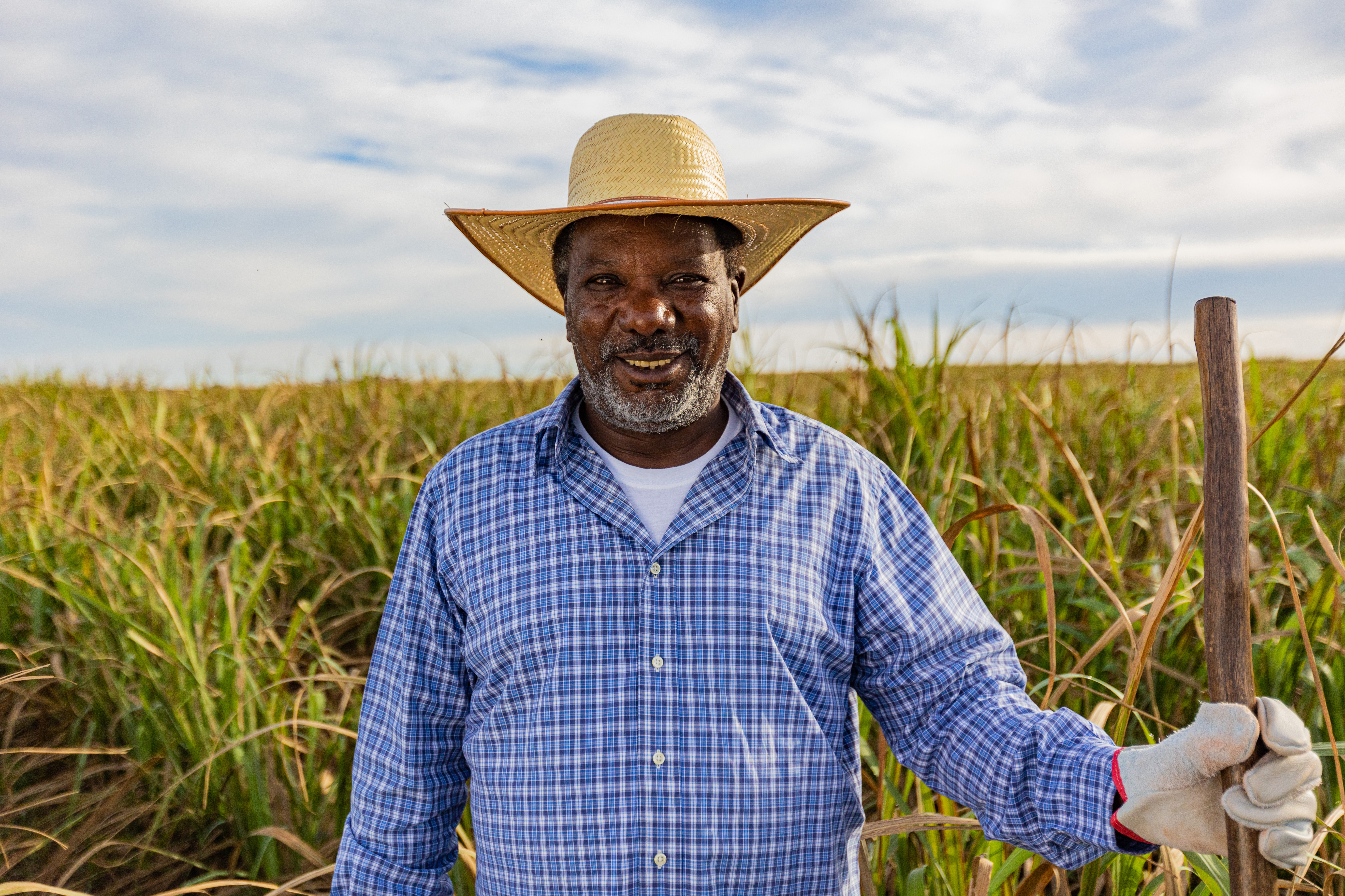 older dark skinned man holding a garden tool staring at the camera