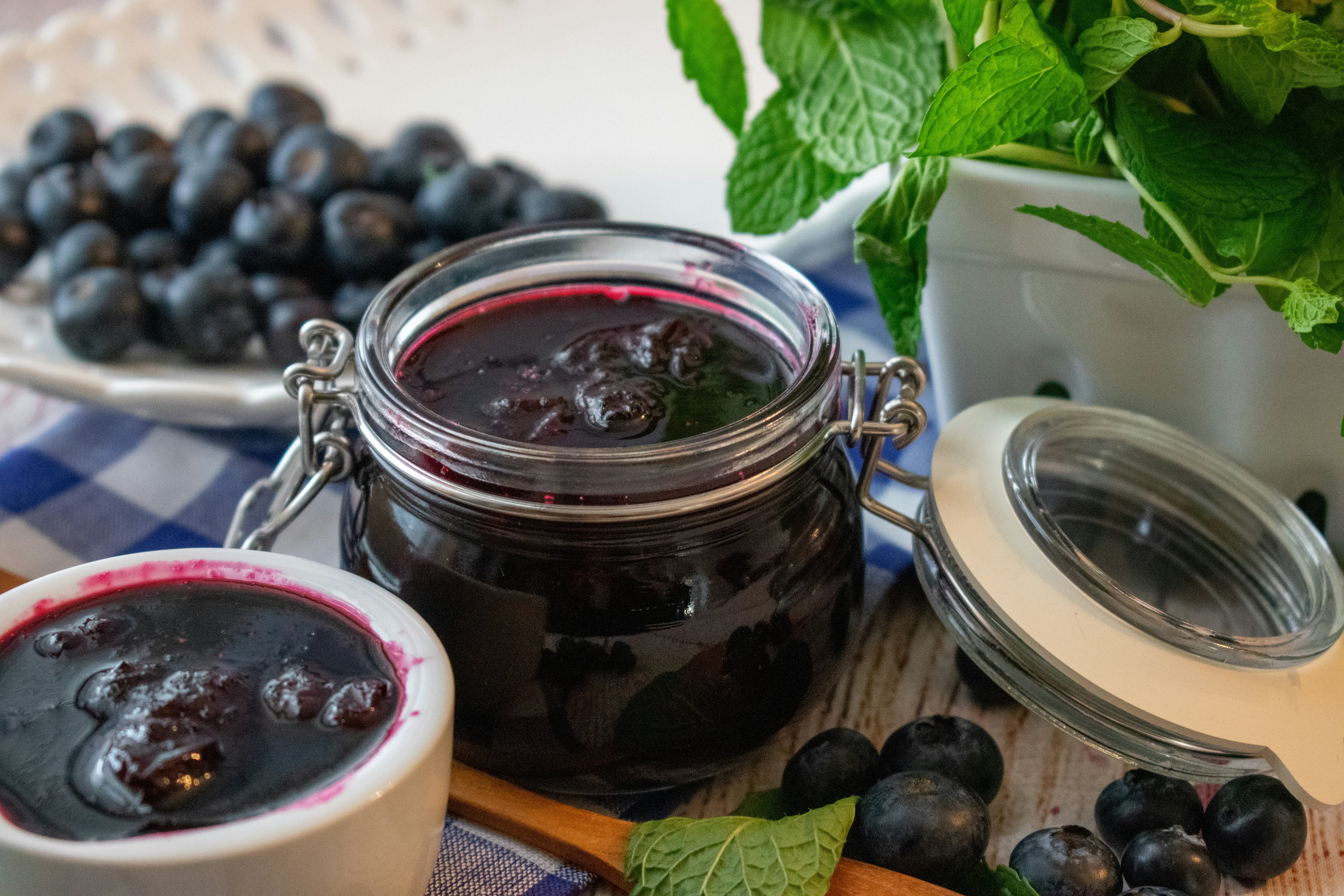fresh blueberries and homemade jam on a table with blue crosshatch table cloth